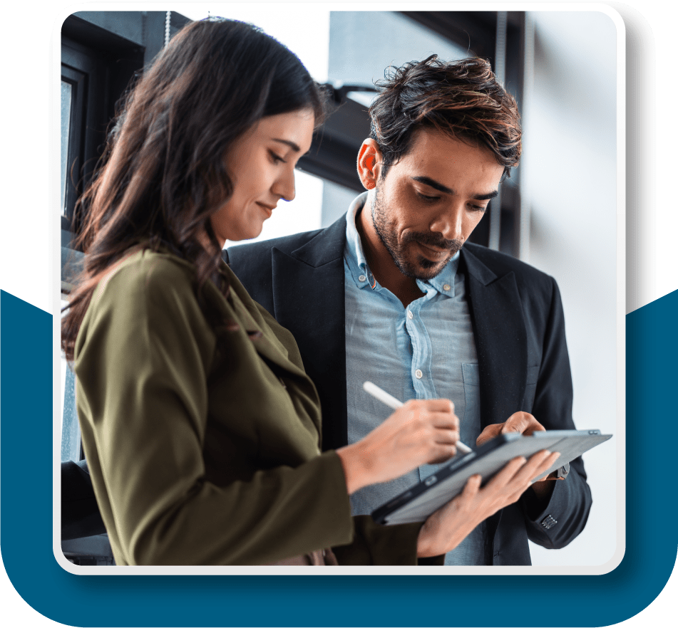 Framed image of a man and a woman reviewing items on the woman's iPad as they walk into the office together.