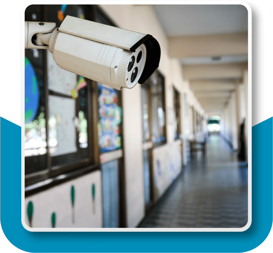 Framed image of a surveillance camera in an empty grade school hallway.