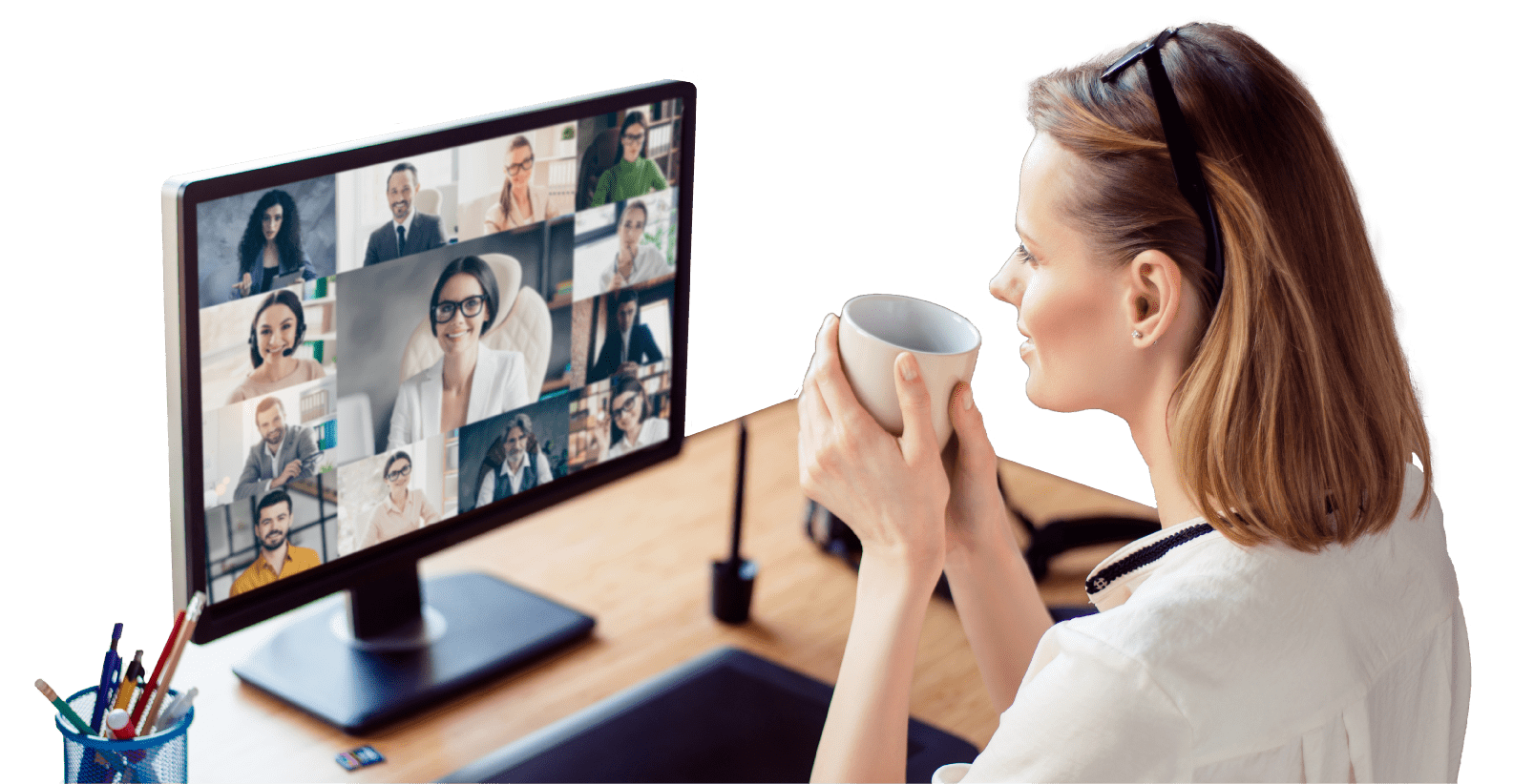 Cut-out image of a woman sitting at her desk on a conference call while sips a cup of coffee or tea. Various people are on-screen on the monitor to her left.