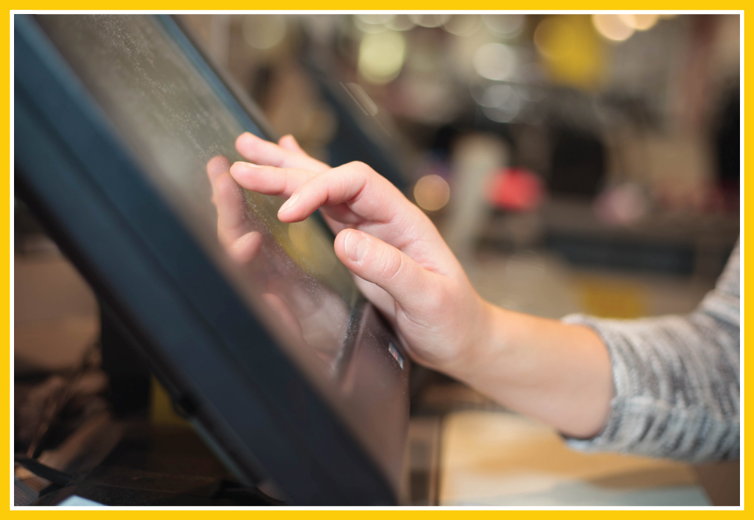Up close shot of a person's hand as they use a touchscreen display in a bank or financial institute.