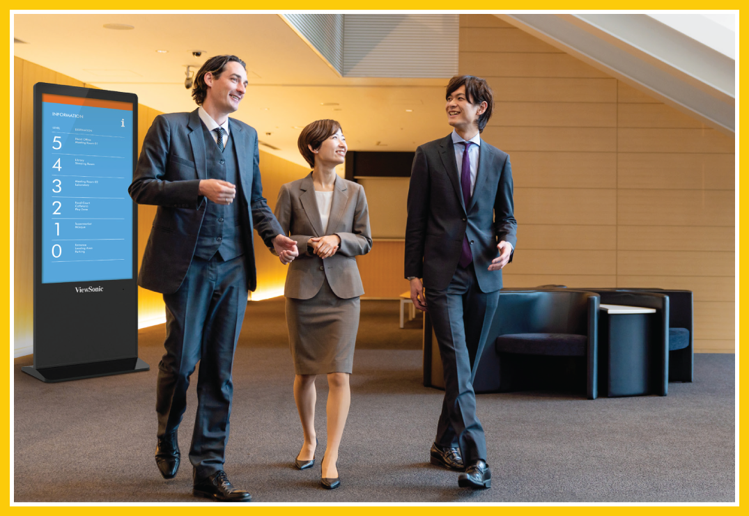 Three government officials walking through a building lobby. Off to the left in the background is a kiosk with navigation information.