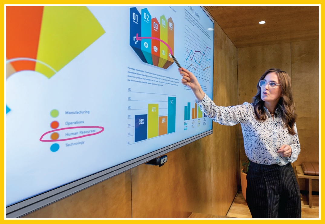 A woman utilizing an interactive display - she's drawing an arrow pointing to different charts and elements on-screen.