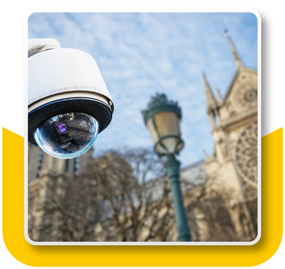 Surveillance camera in the foreground, posted outside of a church building.